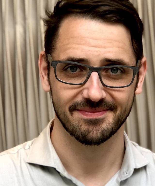 Headshot of Kalle Westerling in front of tan curtain